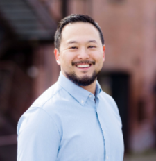 Man smiles wearing a light blue button up