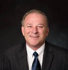 portrait photo of a man in a suit smiling