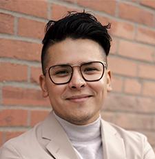 Man with glasses and dark hair smiling. 